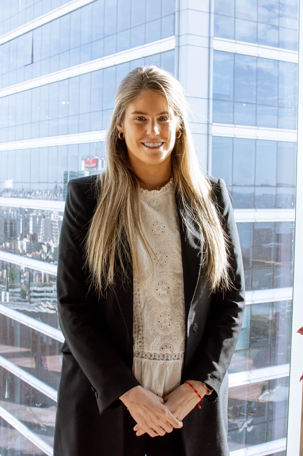 Retrato profesional de Marcela Doria, asesora en InvestaTrust, con fondo de una moderna fachada de oficinas.