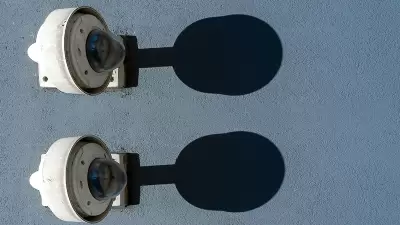 Dos cámaras de seguridad con sombras proyectadas sobre una pared, acompañadas del texto sobre la importancia de los convenios para evitar la doble tributación, reflejando el enfoque preciso y detallado de InvestaTrust en este servicio.