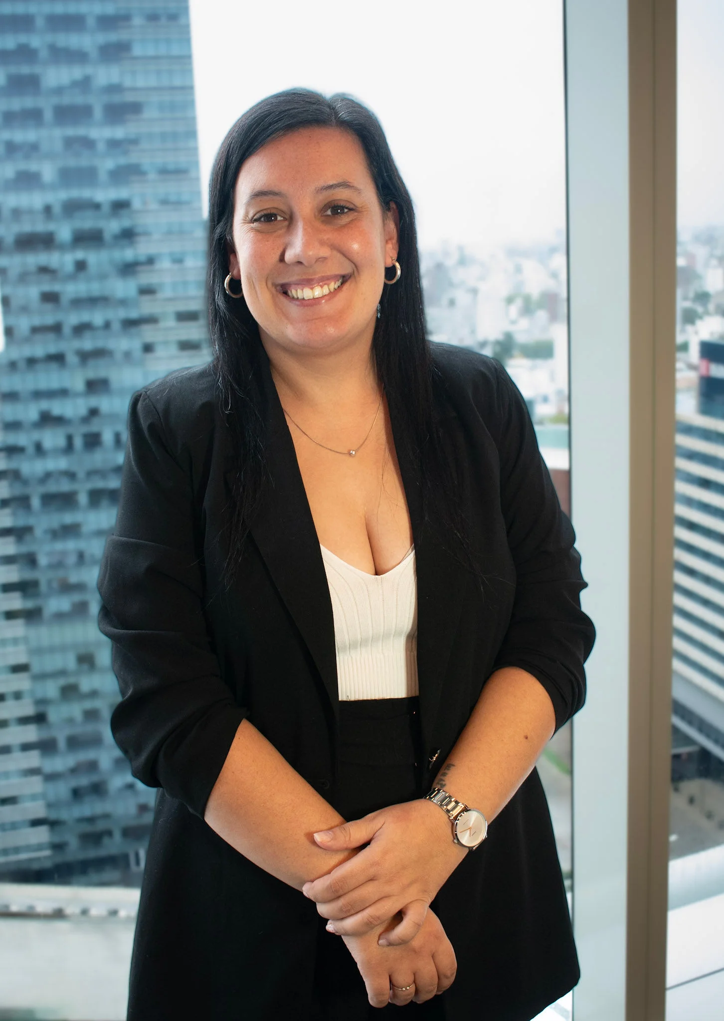 Retrato profesional de Natalia Martinez, asistente contable en InvestaTrust, posando frente a una ventana con vista a un edificio moderno.