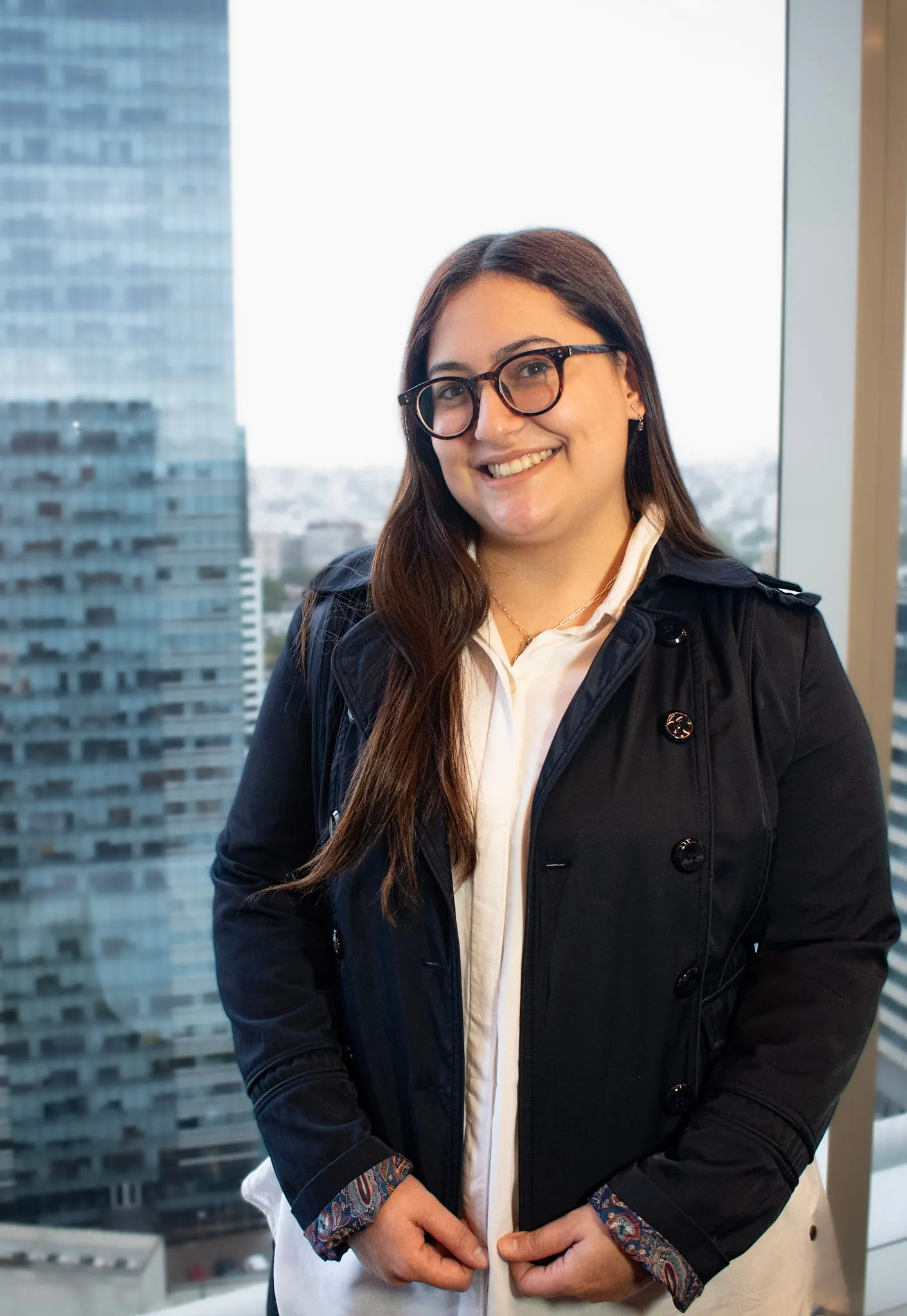 Retrato profesional de Soledad Schiera, asistente legal en InvestaTrust, posando frente a una ventana con vista a un edificio moderno en una ciudad.